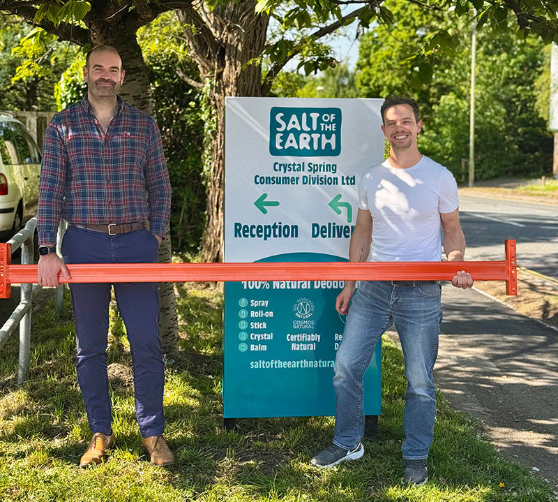 Thomas from Salt of the Earth and Brett Sanders from The Natural Deodorant Co. standing together outside the Salt of the Earth warehouse in Hampshire, holding orange warehouse racking equipment during their collaboration visit