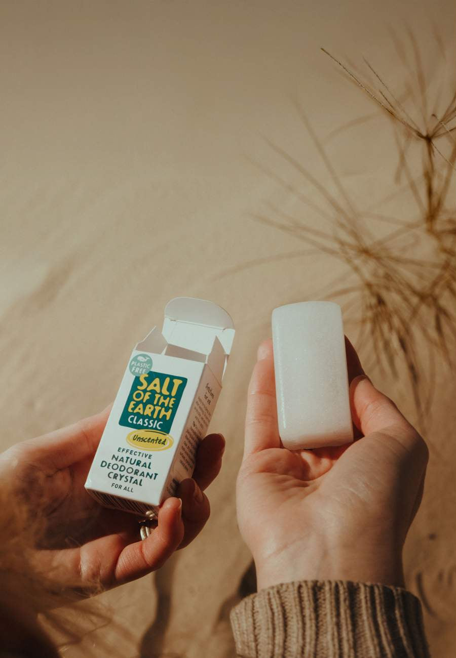 Person holding Salt of the Earth Classic natural deodorant crystal and its packaging outdoors, unscented and plastic-free