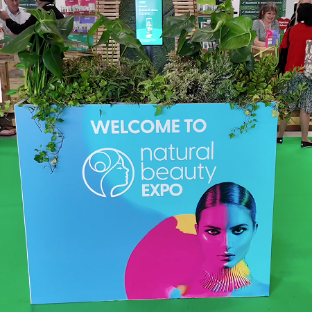 Empty Salt of the Earth natural deodorant exhibition stand F20 at Natural Beauty Expo before setup, showing the white shell scheme booth with blue branded header panels.